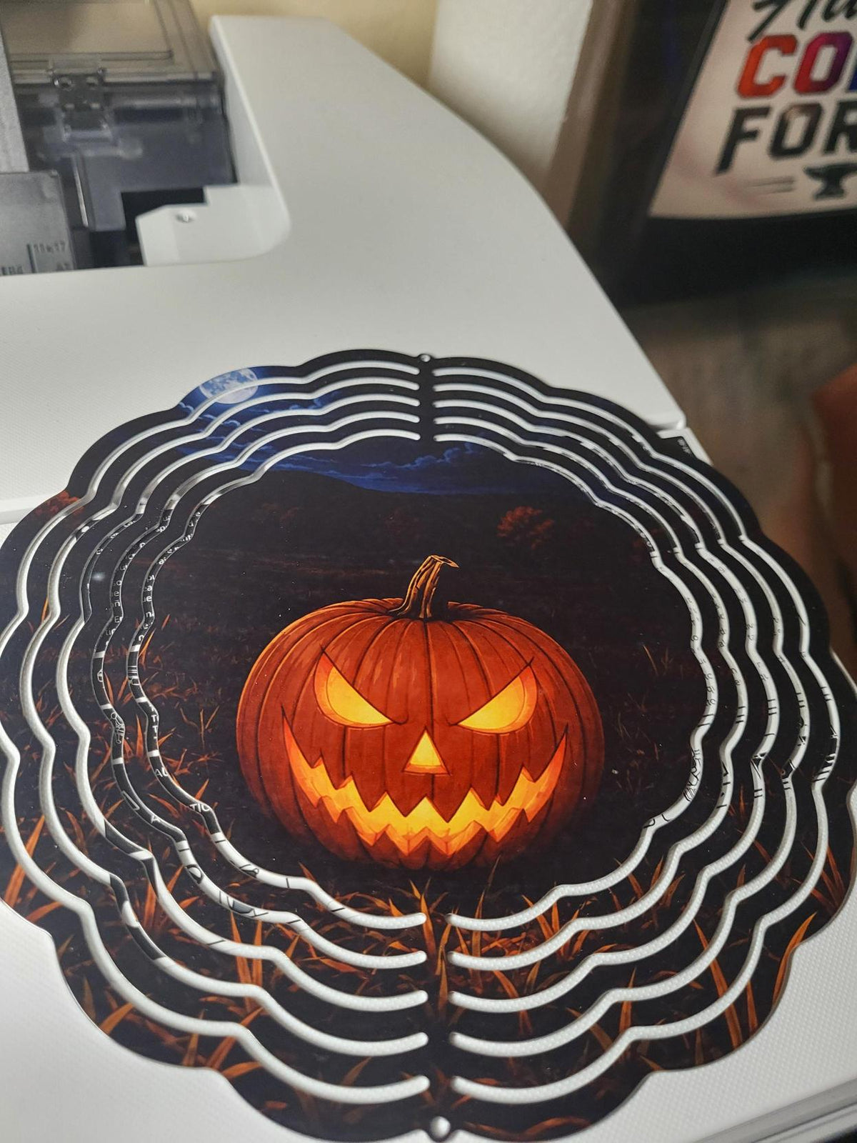 Wind spinner showing a glowing jack-o-lantern with evil carved face against a dark Halloween night sky
