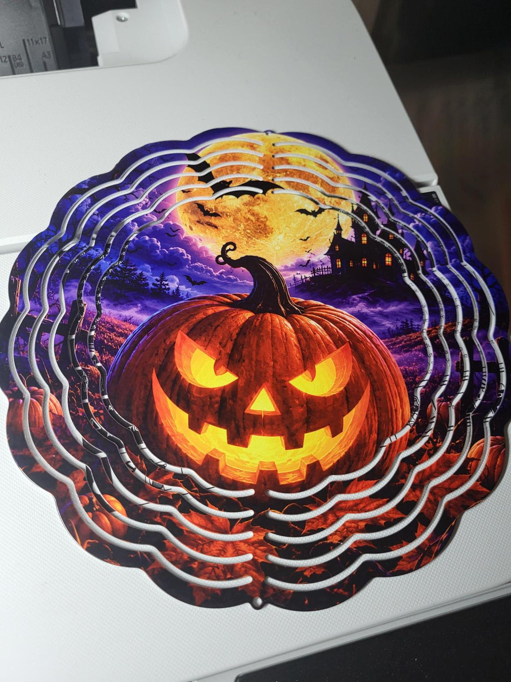 Halloween wind spinner alternate angle showing glowing pumpkin, bats, haunted house and full moon